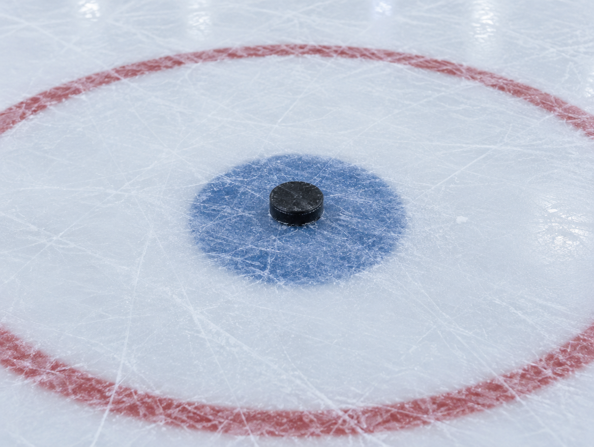 Einzelner Puck auf dem Anspielpunkt im Mittelkreis einer frisch aufbereiteten Eisfläche