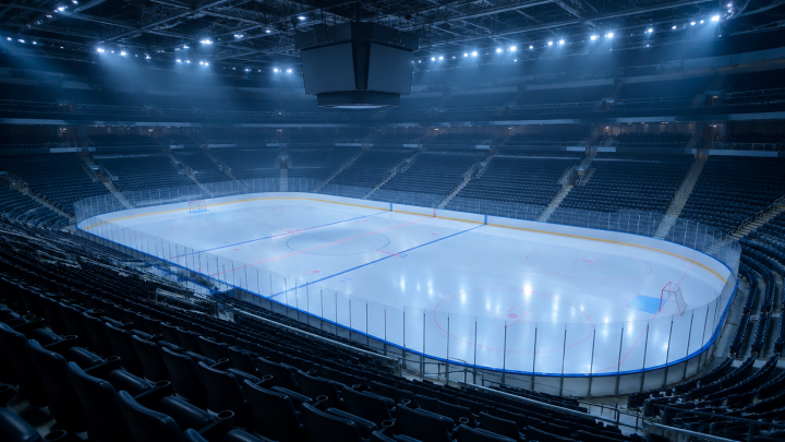 Leere Eishockeyhalle von der oberen Tribüne aus gesehen, frisch präparierte Eisfläche im blauen Hallenlicht